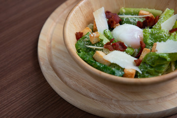 Vegetable salad in a light brown bowl with eggs, bread and bacon on the saucer On brown ground