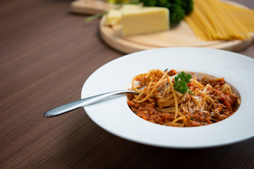 Spaghetti in tomato sauce, served on a plate, parsley in a white dish, on a brown wooden floor,  Italian food