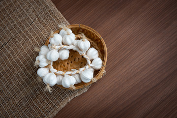 White garlic in the upper basket and placemats On a brown wooden floor