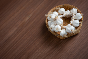 White garlic in a basket Laid on a brown wooden floor