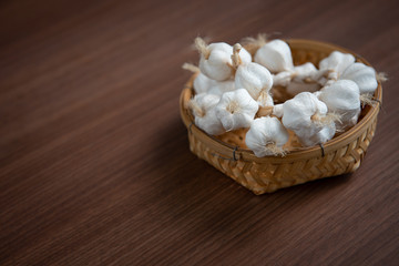 White garlic in a basket Laid on a brown wooden floor