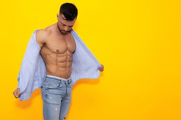 Fitness model wearing jeans, posing and taking off her shirt