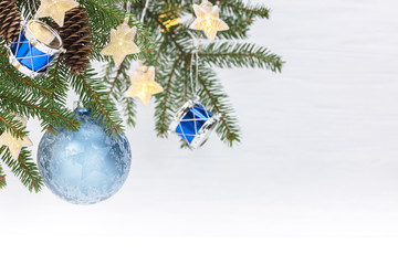 christmas tree branch with blue glass ball, decorative drums toys and star light garlands against white background