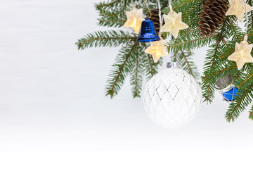 Fototapeta na wymiar beautiful winter background with green christmas tree branch decorated with drum toys, white glass ball and light garlands