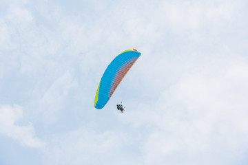 A blue paraglider flies freely in the blue sky