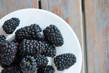 top view on fresh blackberries in white plate