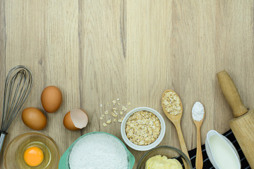 tools and ingredients  for baking cake (flour, butter, eggs, milk, Oatmeal) on wooden background. Top view with copy space.