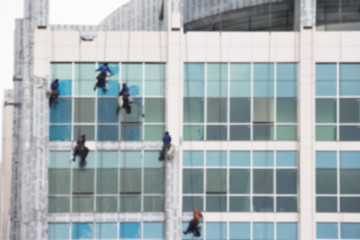 workers cleaning windows service on high rise building, blur background