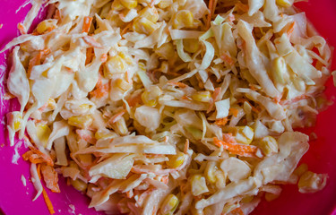 Salad with cabbage and corn and carrots with mayonnaise in a bowl. Culinary background.