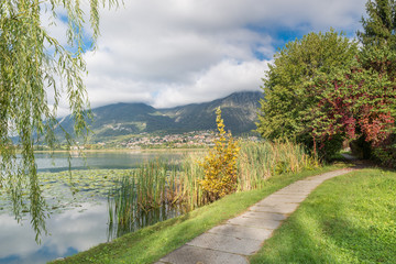 Beautiful Italian lake. Lake Annone or lake Oggiono and pedestrian cycle track near the small town of Sala Al Barro, with the town of Civate in the background. Lake of glacial origin