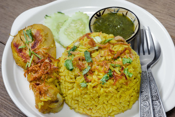 Chicken Biryani with cooked turmeric jasmine on wood background