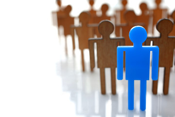 Male blue plastic toy businessman silhouette wooden crowd figure background closeup. Manipulate...
