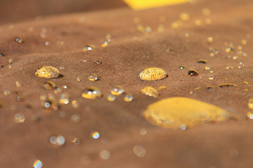 drops of water on the brown suede reflecting the yellow wall