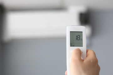 Male hand hold remote air conditioning background. Repair and maintenance of ventilation concept.