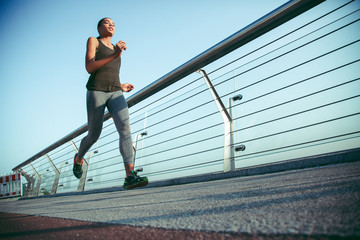 Female athlete jogging on the bridge stock photo
