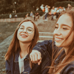 Two pretty young friends happy smiling in the city park