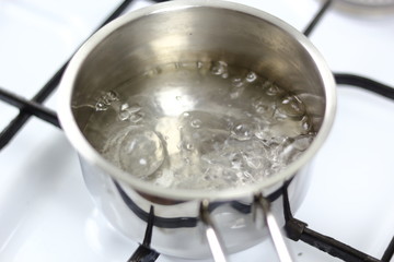 Boiling water in milk pan on gas stove