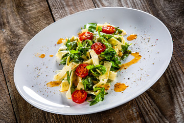 Pasta with tomatoes and arugula on wooden table
