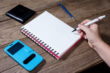Human hand holding pen with open note book