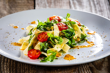 Pasta with tomatoes and arugula on wooden table
