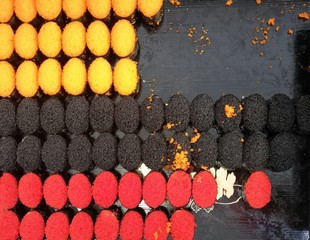 Black orange and red caviar sushi, placed on a black tray