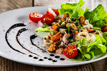 Salad with seafood and vegetables on wooden table