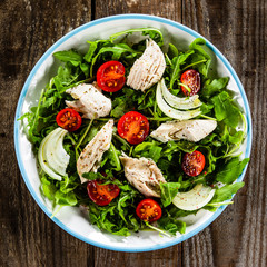 Salad with chicken meat and arugula on wooden table