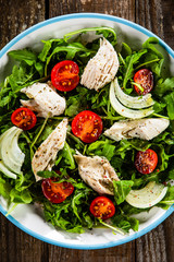 Salad with chicken meat and arugula on wooden table