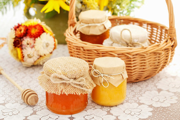 Glass jars with honey on the table and sunflowers in the background.
