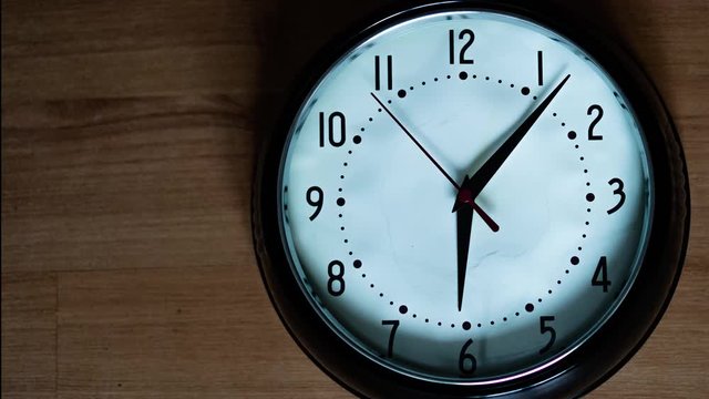 Oval black and white classic analog clock with red second hand going slowy arround. Passing the time time lapse