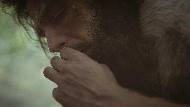 Primeval Caveman Wearing Animal Skin Holds Stone Tipped Spear Looks Around, Explores Prehistoric Forest in a Hunt for Animal Prey. Neanderthal Going Hunting in the Jungle