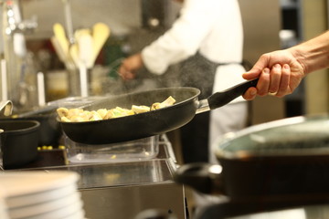 professional cook in kitchen preparing food for customers showing hands and utilities