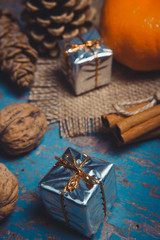 Obraz na płótnie Canvas Christmas decoration with gifts, pine cones, tangerine, cinnamon sticks and walnuts