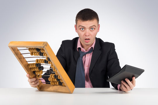 Frustrated young businessman with calculator and abacus