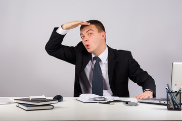Young businessman holding his hand at forehead and looking forward