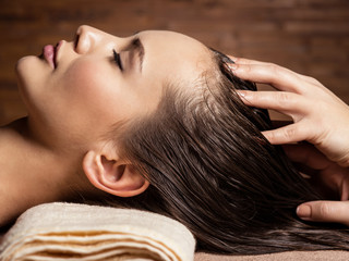 Masseur doing massage the head and hair for an woman in spa salon