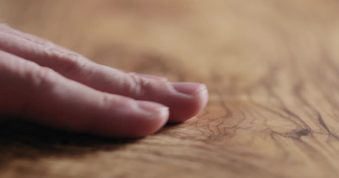 Slow motion man hand touch oil finished olive wood surface