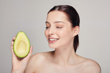 attractive happy and cheerful brown-haired nude lady with perfect pure shine skin with avocado in the right hand