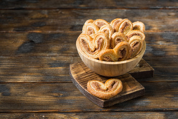 Puff pastry with sugar and cinnamon in a wooden bowl. Rustic style. Space for text