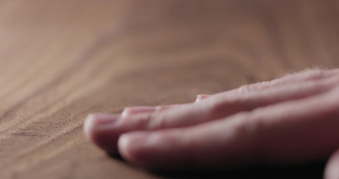 Slow motion man hand touch oil finished black walnut wood surface