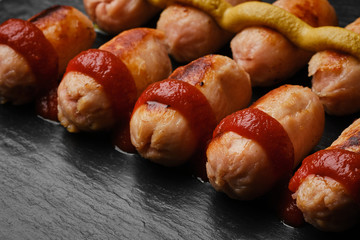 grill sausages with ketchup and mustard on black stone background