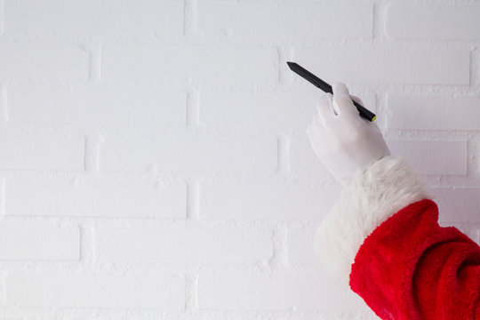 Santa Claus writing with the pen on the white brick wall