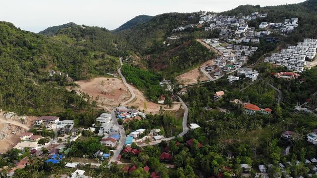 Tropical terrain covered with endangered forests and luxury villas. Drone view of large tropics with ecosystem disturbance due to buildings and deforestation. Koh Samui. Coconut palm plantations