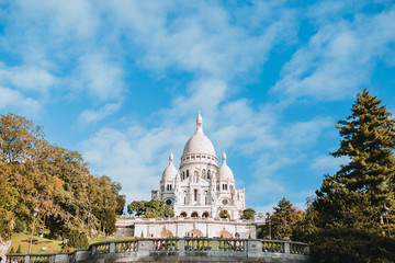 Fototapeta premium Bright sunny day bottom view from Montmartre to the Sacre Coeur Basilica - majestic against the blue bright sky