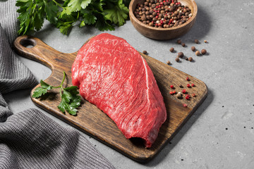Raw beef meat on a wooden Board on a gray kitchen table