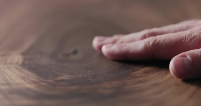 Slow motion man hand touch oil finished black walnut wood surface