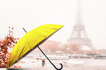 Yellow umbrella on a cloudy rainy autumn day on the banks of the Seine on the background of the Eiffel Tower