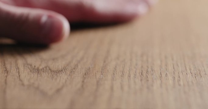 Slow motion man hand touch oil finished oak wood surface