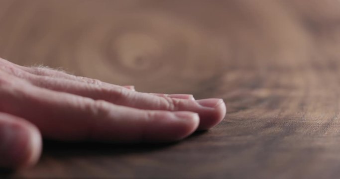 Slow motion man hand touch oil finished black walnut wood surface