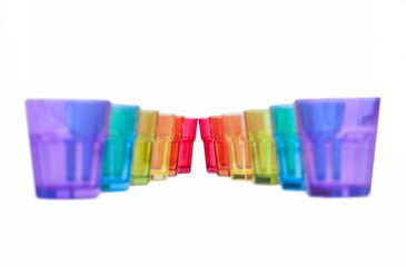 multi-colored glass on a white background. containers made of glass, ordered by the rainbow color spectrum, isolated, purple, blue, green, yellow, orange, red, with clipping path.